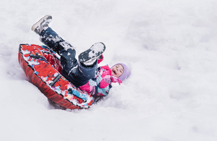 Happy girl slid down on snow tube and funny fell upside down