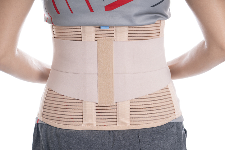 young woman wearing back support for protect her back, medicine and healthy concept.
