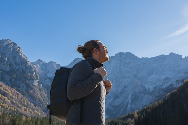 Young man walks down road in mountains