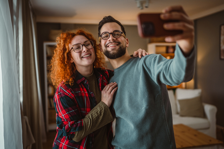 Self portrait of beautiful happy couple stand, smile and hug at home