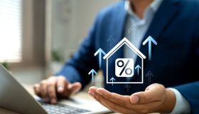 Real estate market growth, Hand holding house model with upward arrows and percentage signs, Symbol property investment and mortgage rate trends. Property investment insights, Future in housing market