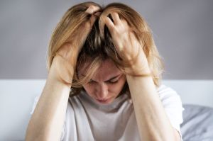 Stressed blonde woman with hands on head having a migraine headache. Mental stress and pain concept video