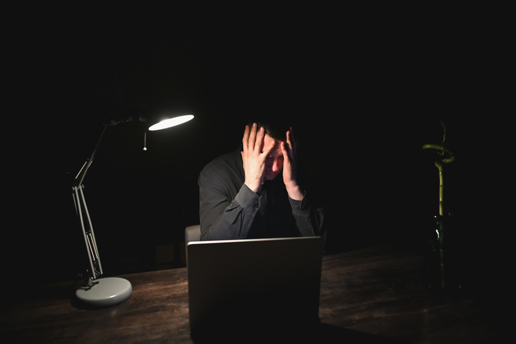 Stressed businessman holding his head in his hands in dark office