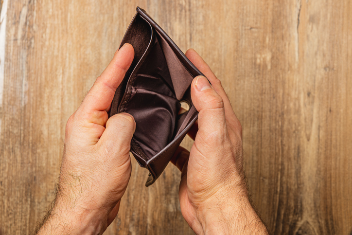 Struggling businessman confronts financial crisis with empty wallet in hands