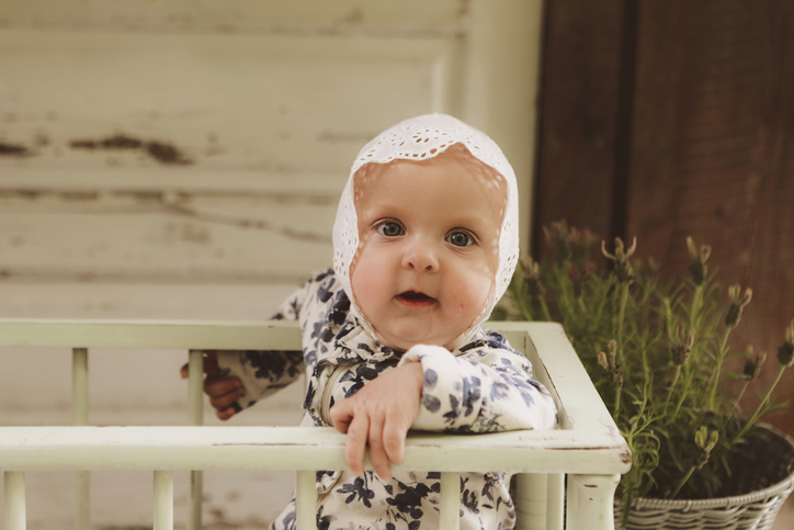 Baby Girl Wearing Bonnet in Vintage Crib