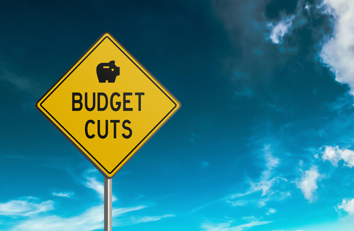 Budget Cuts road sign on sky background