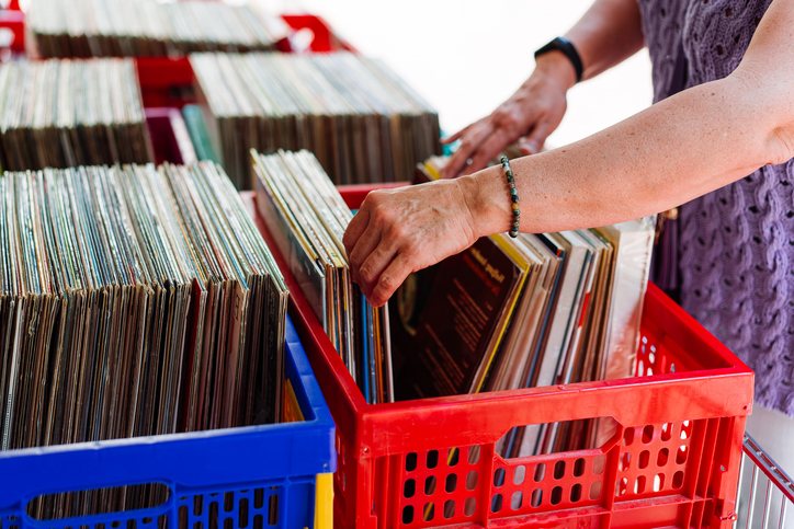 Woman Browsing Colorful Vinyl Records in Crates at a Market Stall