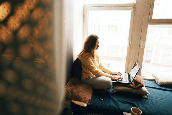 Young Woman Working on Her Laptop by a Bright Window