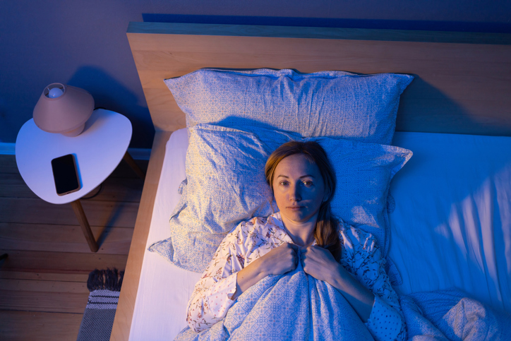 lady in bed can't sleep. sleep problems caused by stress and fatigue. woman in bed alone empty space