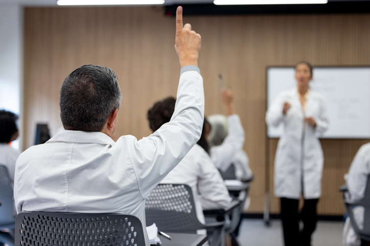 Doctor raising his hand to ask a question in a seminar