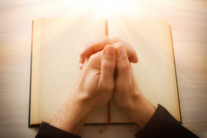 Praying with hands over religious book on table top view,Municipalityof Valdemoro,Community of Madrid,Spain