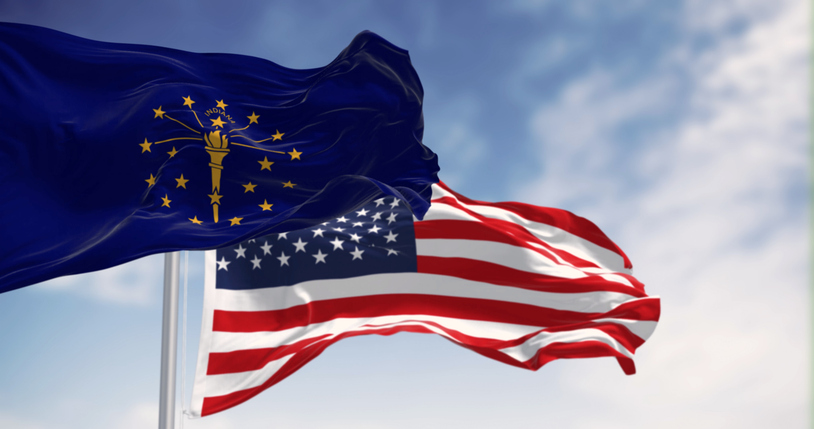 Indiana state flag waving with the national flag of the United states on a clear day