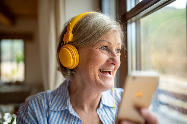 Senior woman with headphones, listening music.