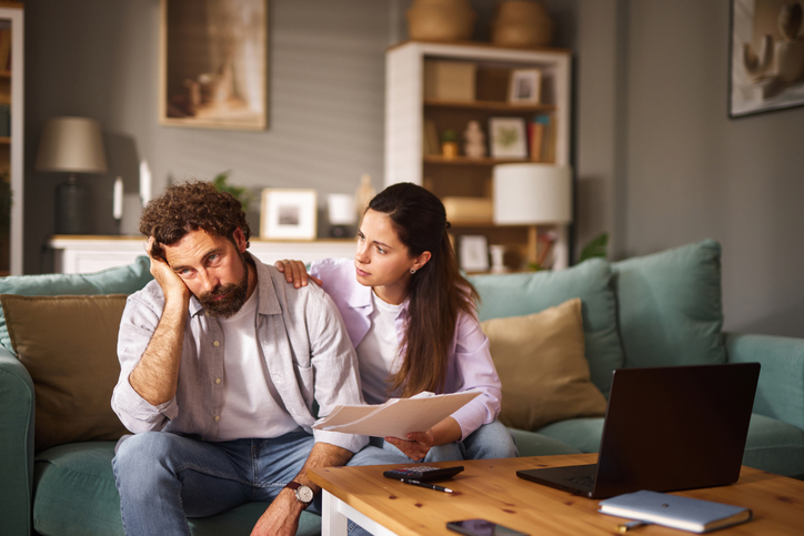 Worried couple examining financial documents at home