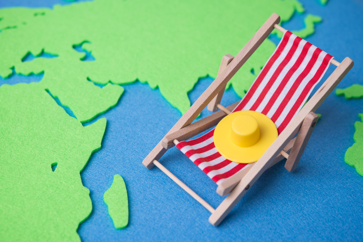Red beach chair and hat on world map background copy space.