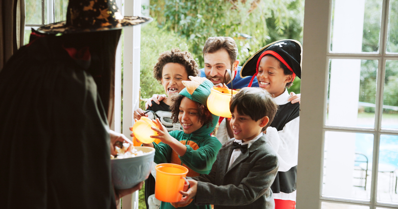 Children, happy and candy at door on halloween for tradition, costume and trick or treat. Holiday, neighborhood kids and excited with bucket at house for sweets collection, dress up and celebration