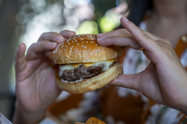 Close-up of hamburger in hands of young woman.