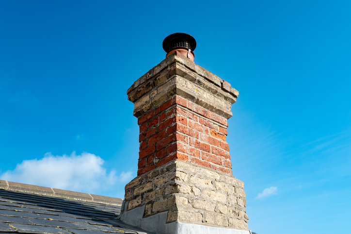 Close-up of an old, brick built single chimney on a residential roof in the UK.