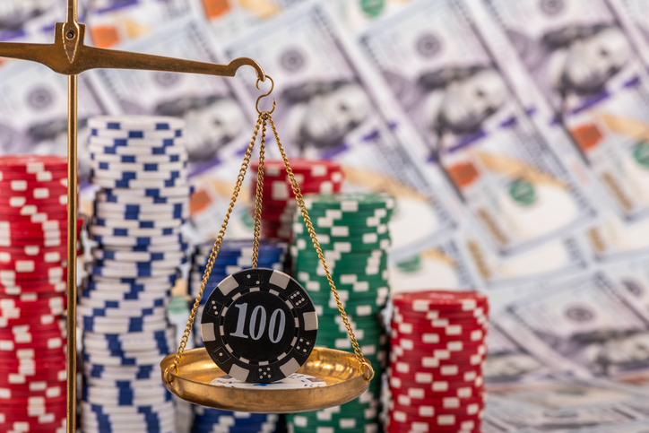 A conceptual story about ludomania (gambling addiction) with a golden scales and casino betting chips against a background of $100 bills.