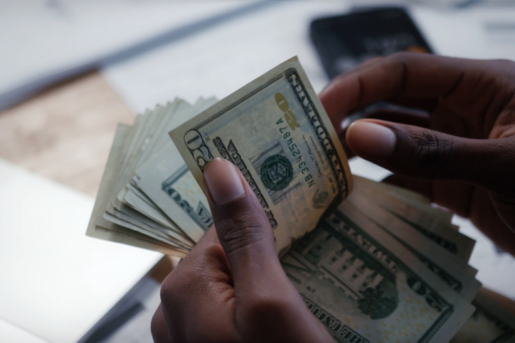 Hands counting US dollar cash on desk