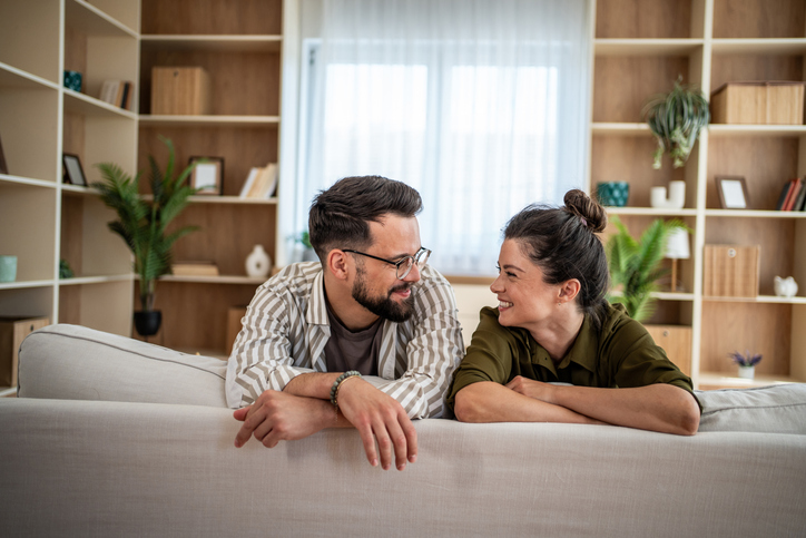 Happy young couple smiling and talking on sofa at home