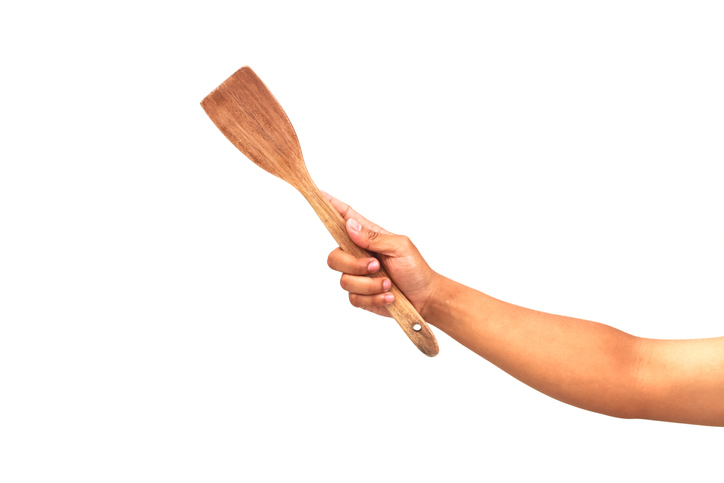 Isolated shot of a human hand holding a wooden spatula ready for cooking action