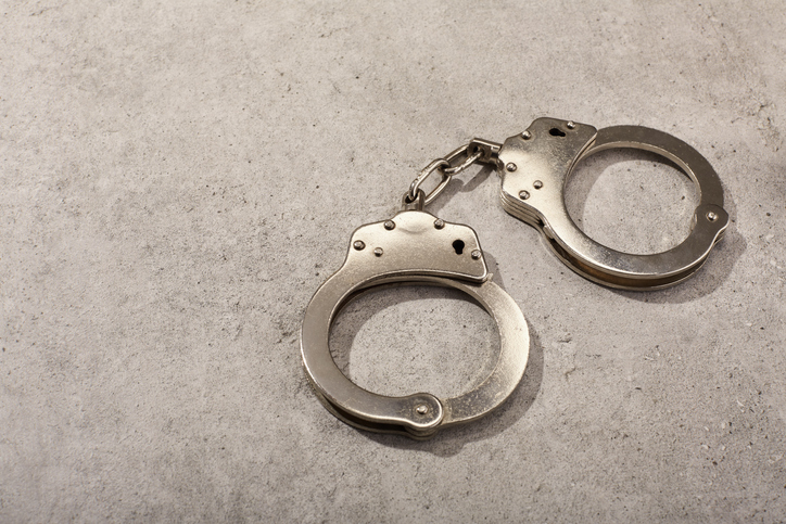 Handcuffs on concrete background under harsh light