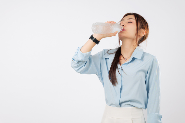 Young attractive woman with a bottle of water, asian and enjoy drink, eyes closed