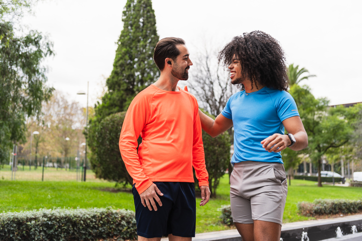 Two men talking after running in park