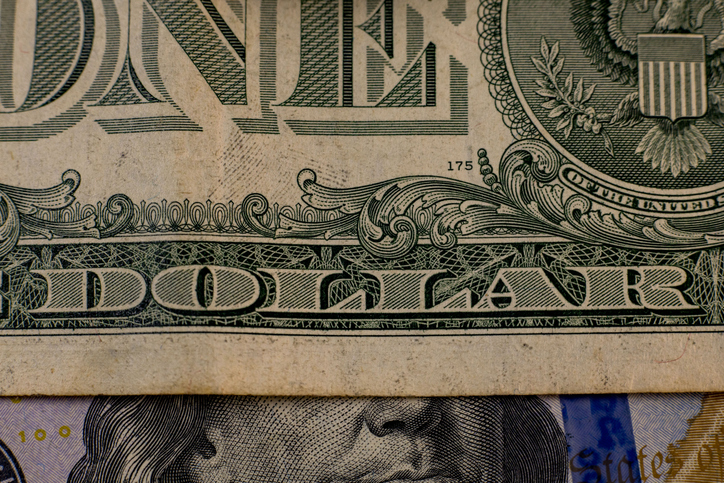 Detailed view of a one dollar bill showing intricate designs and the word dollar prominently displayed in the center of the currency note