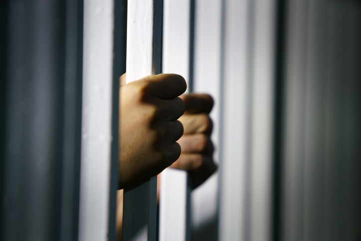 Hands Grasping Jail Bars in Shadowy Light with Dramatic Effect