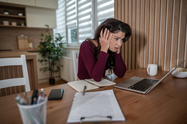 Stressed woman experiencing frustration looking at laptop