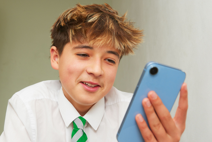 Happy schoolboy on mobile phone.