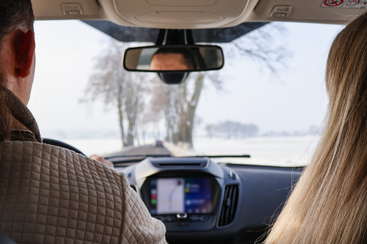 Back view of couple traveling by car through a snowy winter landscape.