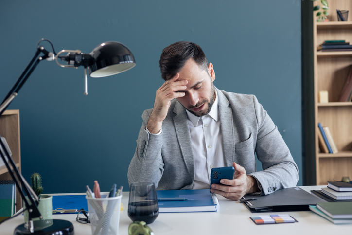 Businessman experiencing stress and headache checking phone
