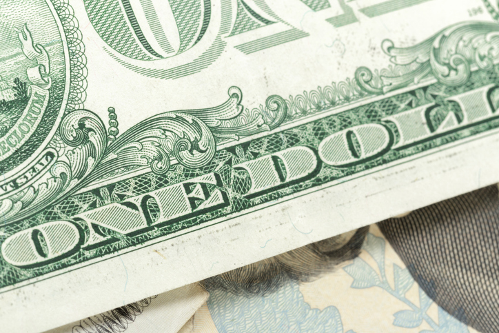 Money displayed close up showing details of a dollar bill and other currency notes underneath