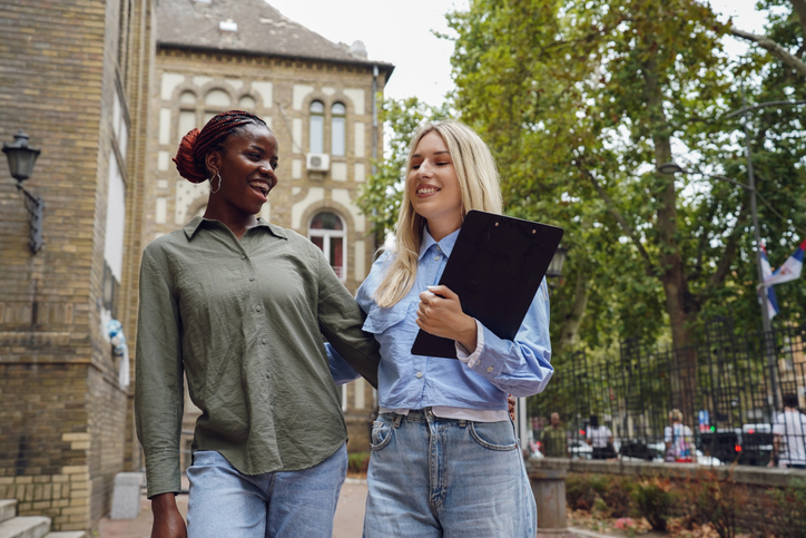 Two Female Students Having Fun in a University Courtyard