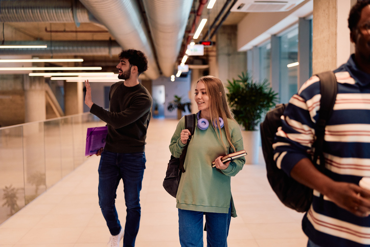 Diverse students walking college campus hallway discussing class