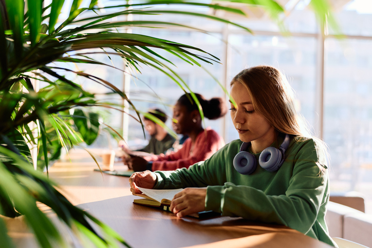 Young female student reading book in university library