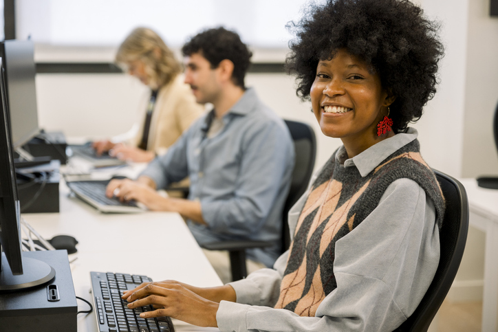 Smiling student using computer in classroom setting
