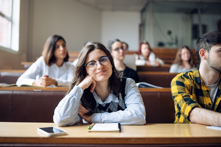Portrait of young student in class with her classmates in lecture hall.