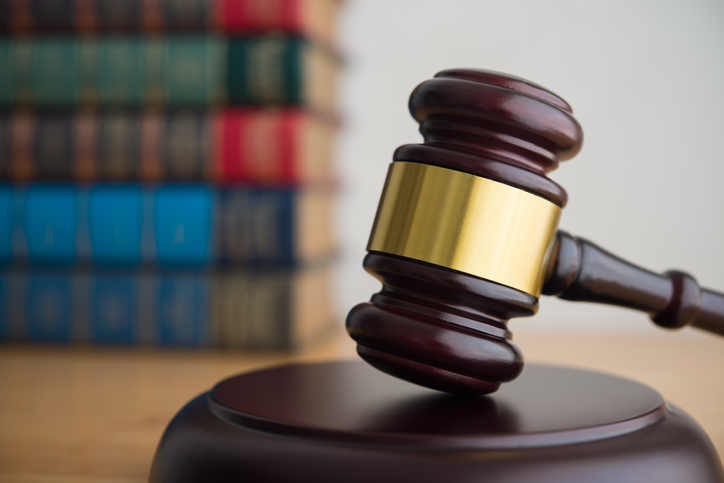 Judge gavel hammer on wooden table with textbooks background.