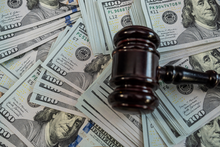 Judge gavel on stacks of US dollar bills symbolizing justice, corruption, financial crime and law