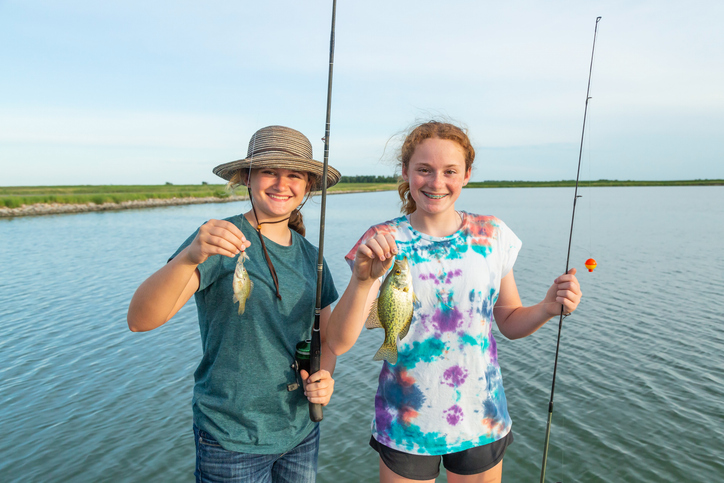 Teenage Girls Holding Fish They Just Caught