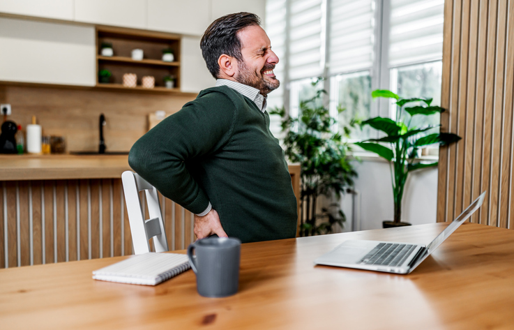 Mature man suffering from back pain working from home