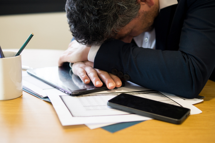 Overworked Businessman Sleeping on Desk with Tablet and Documents
