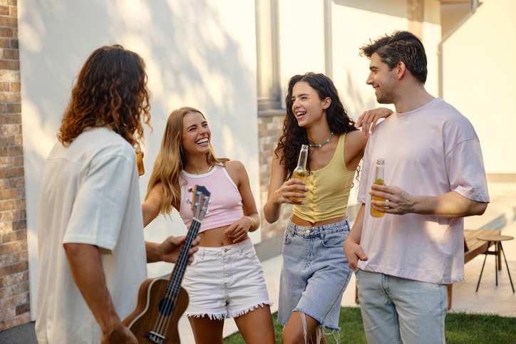 Young friends laughing during live acoustic music at backyard summer party