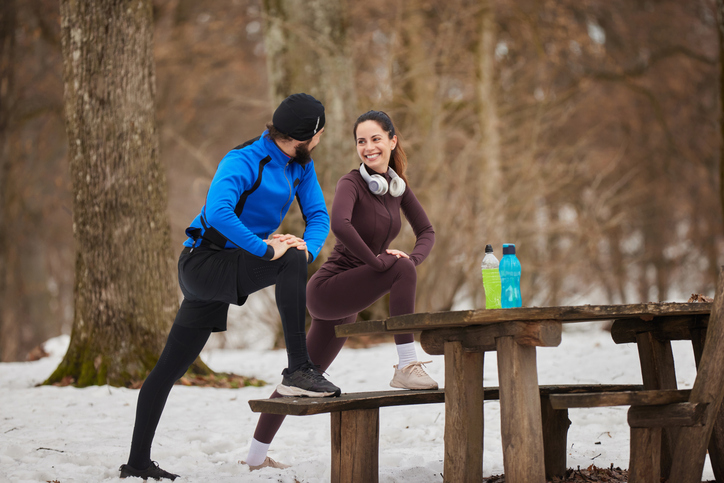 Couple stretching in winter forest after workout