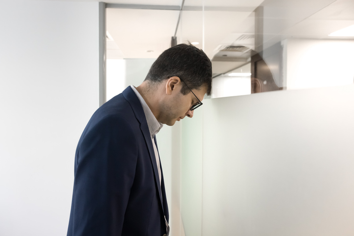 Businessman feeling emotional exhaustion leans head against wall