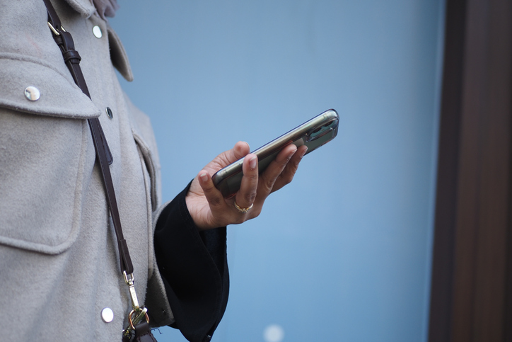 Woman holding phone near wall during casual outing